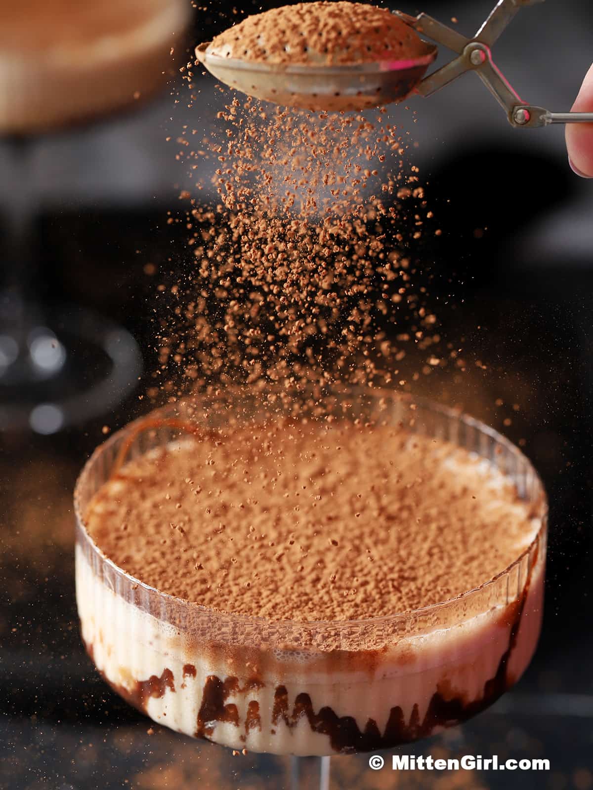 An excessive amount of cocoa powder being dusted onto a cocktail.