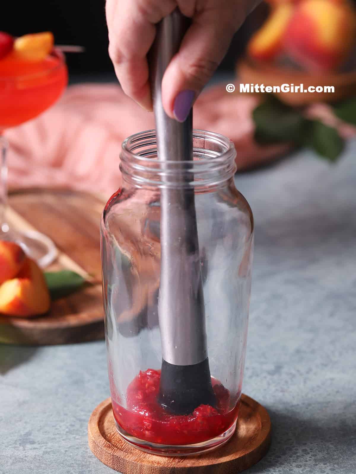 Muddling raspberries and lime juice.