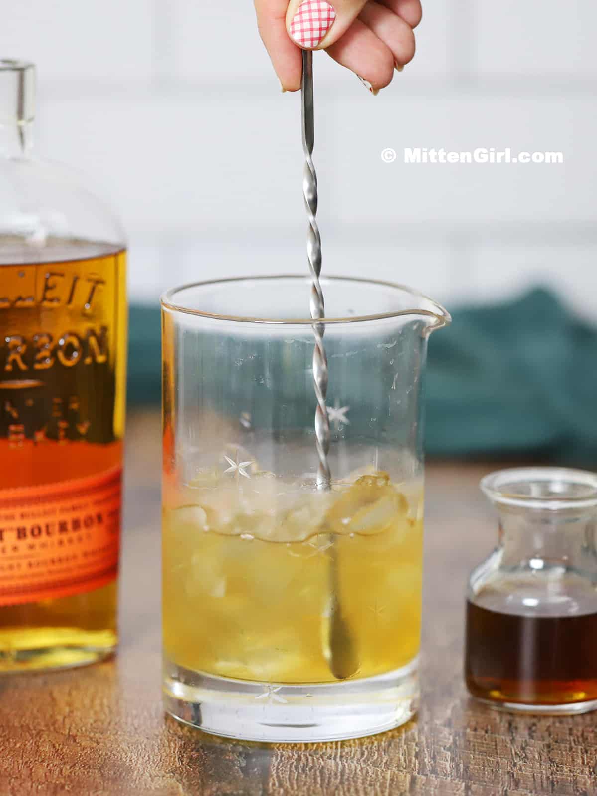 Bourbon being stirred in a mixing glass filled with ice.