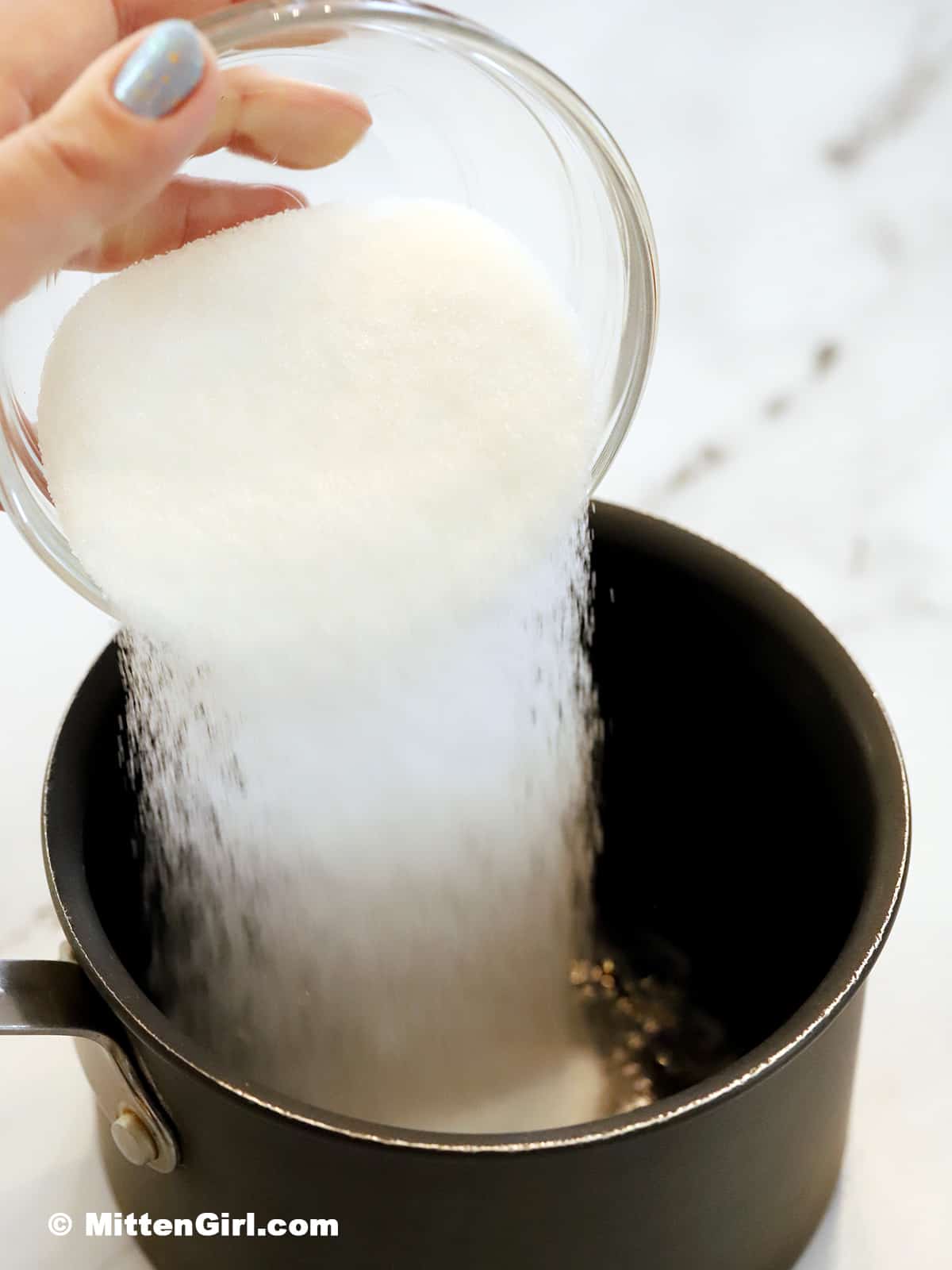 Sugar being poured into a small pot.