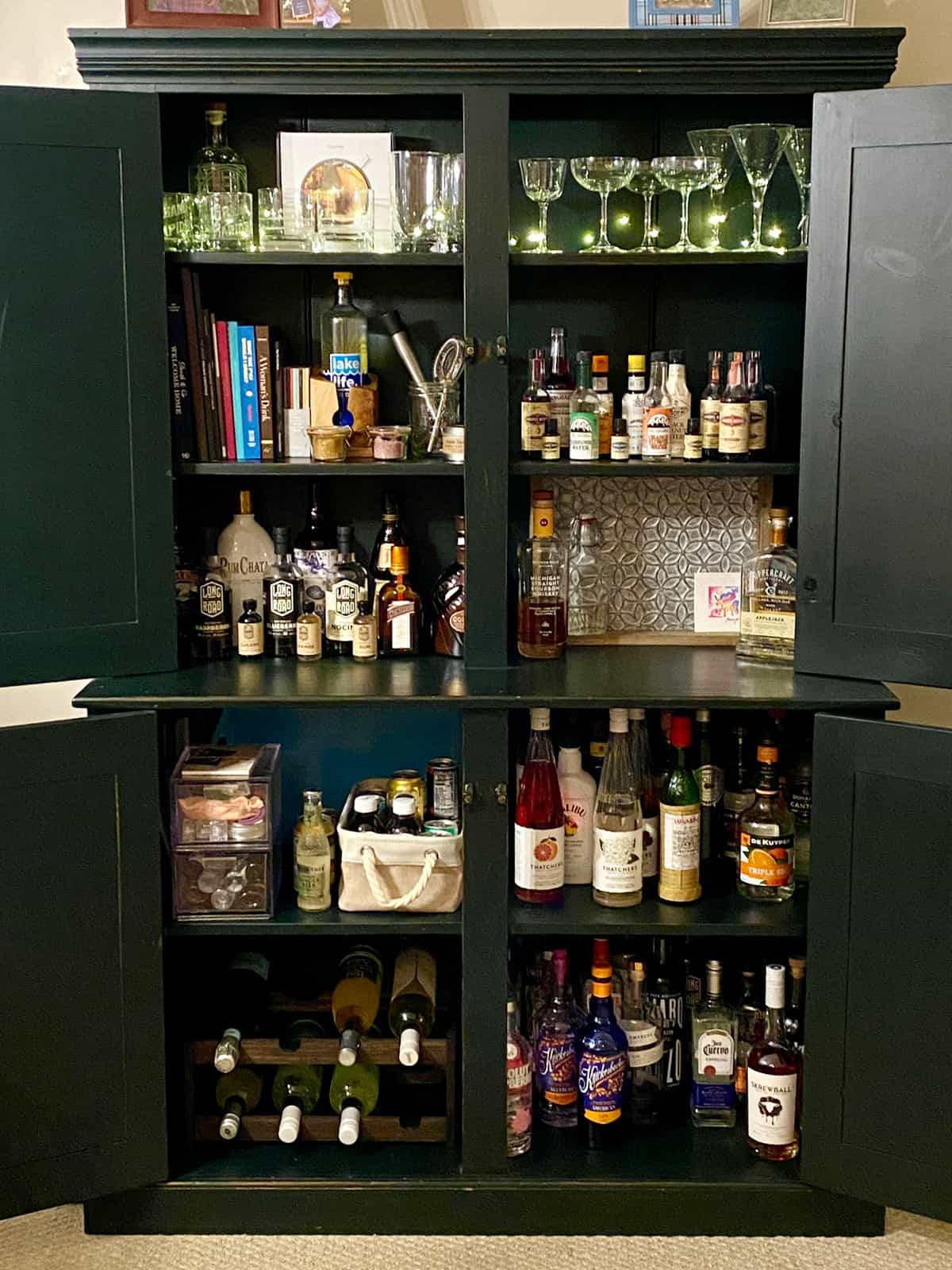 A home bar cabinet, open to reveal its contents. 