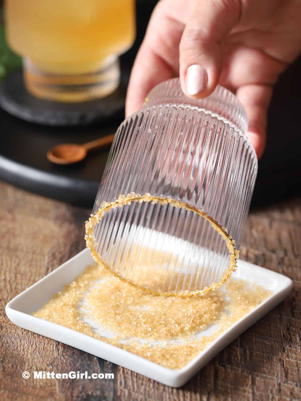 Dipping the rim of a glass in a small plate of raw sugar.