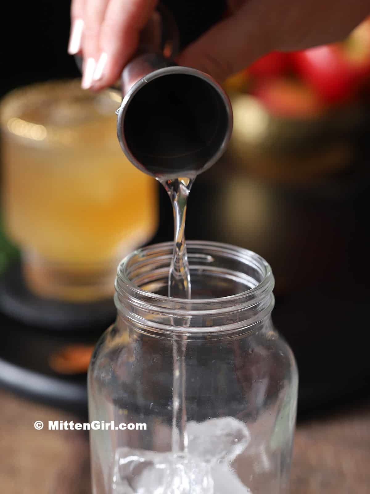 Ginger syrup being poured into a cocktail shaker. 
