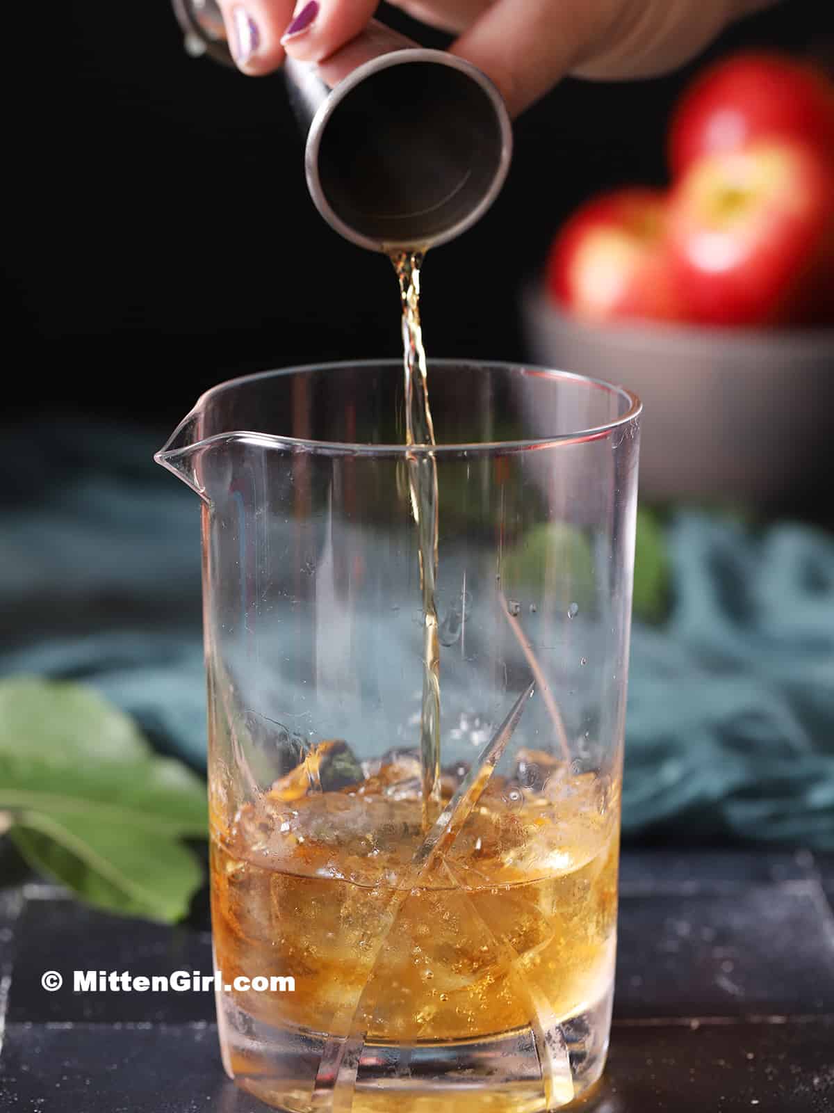 Bourbon being poured into a mixing glass with ice.