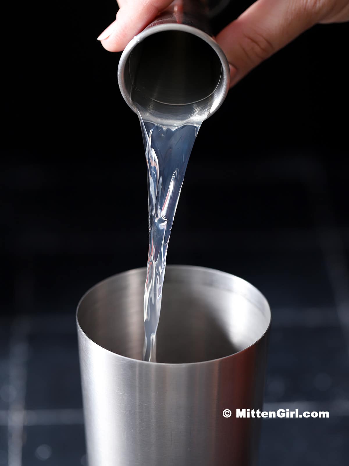 Apple vodka being poured into a cocktail shaker.