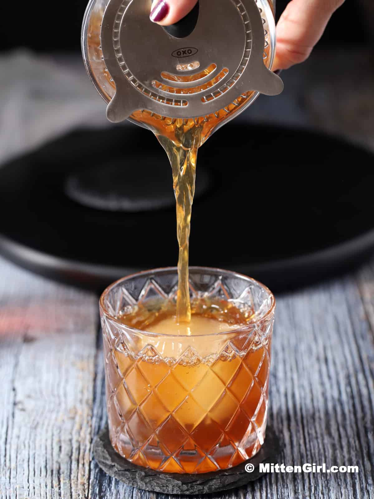 Straining a coffee old fashioned into a rocks glass.