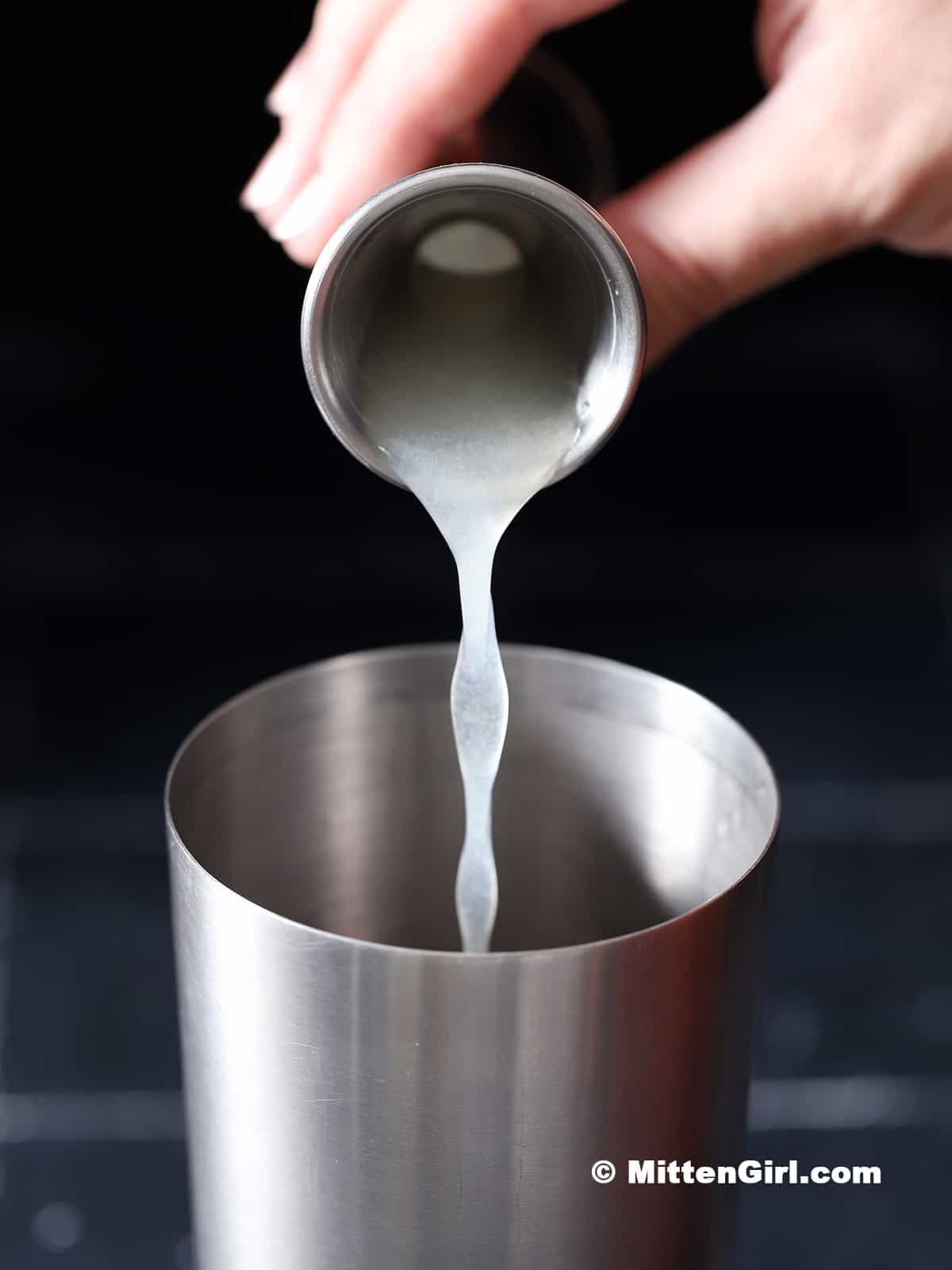 Lime juice being poured into a cocktail shaker. 