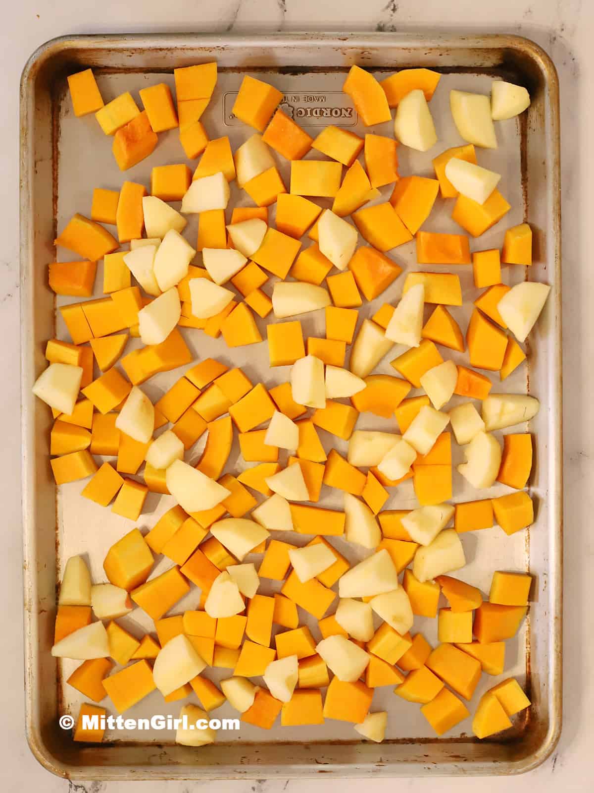 Apples and squash on a sheet pan.