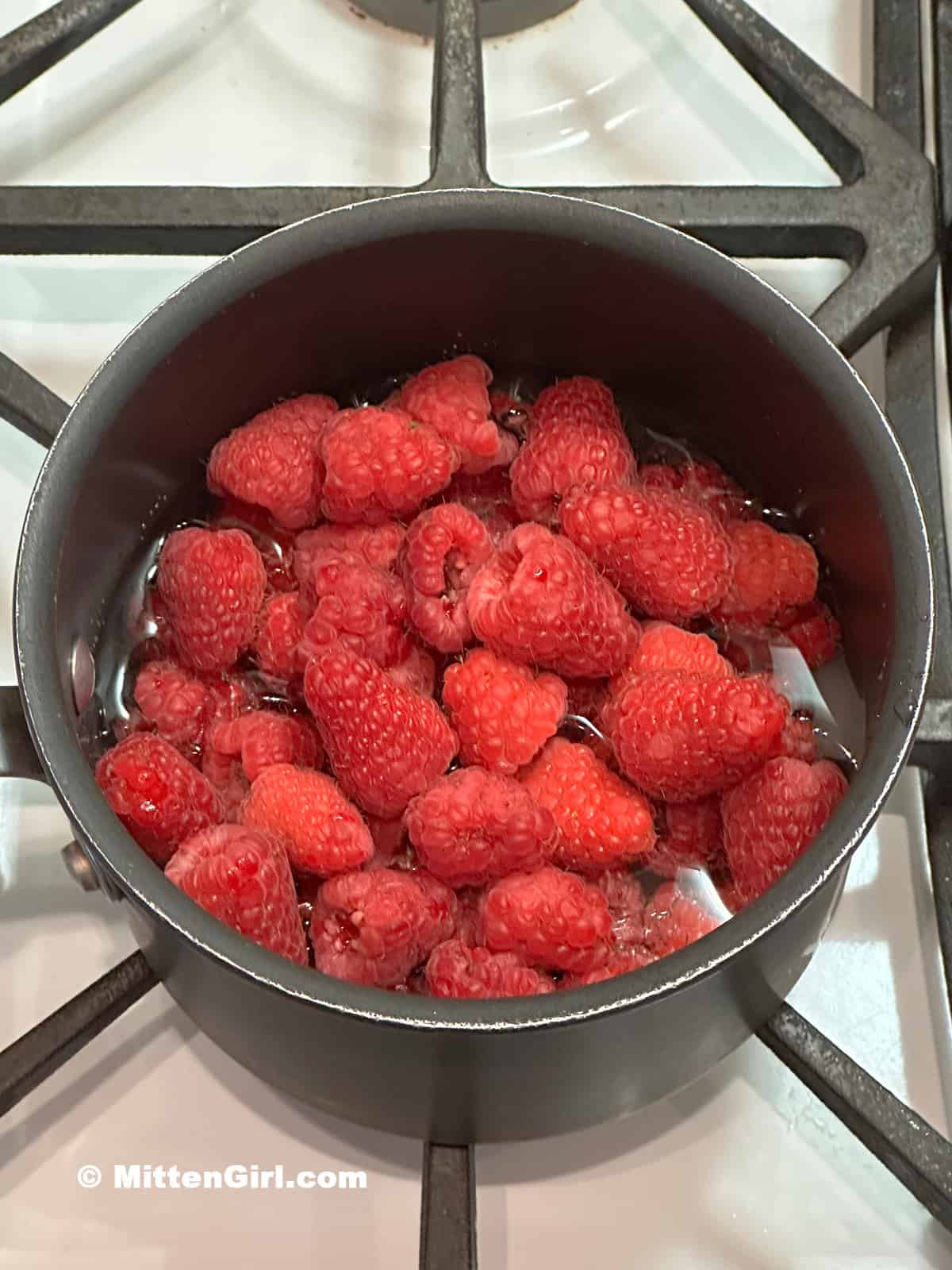 Raspberries in a small pot of sugar and water.