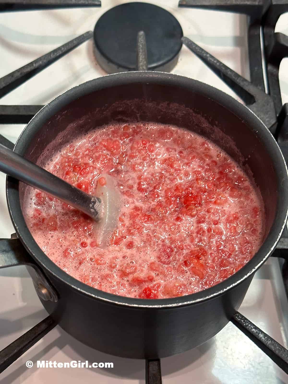 Raspberry syrup cooking and foaming up.