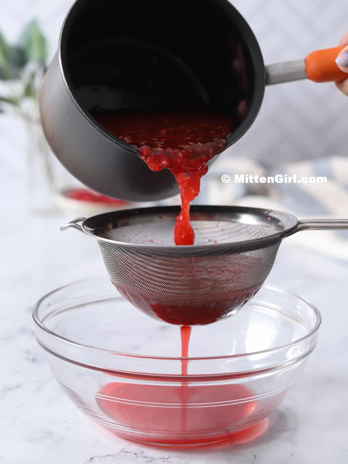 Straining the raspberry syrup mixture.