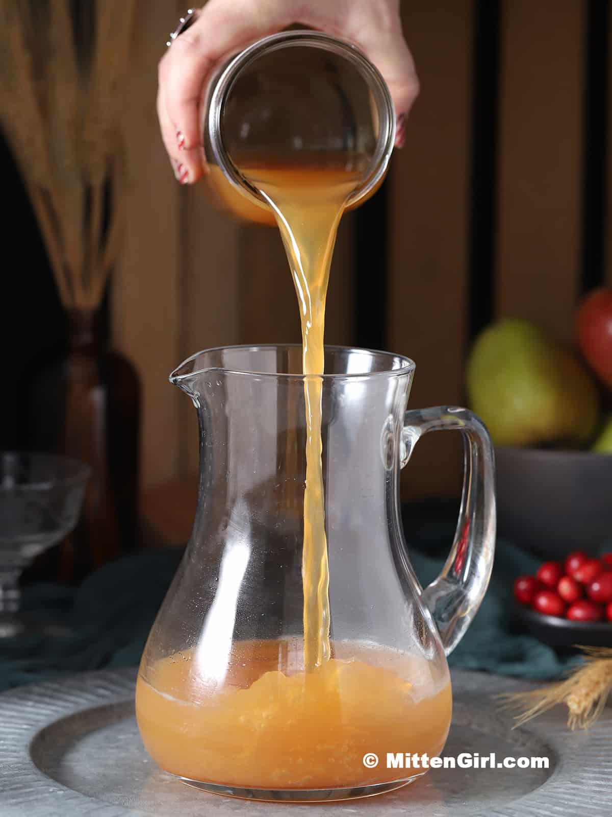 Apple cider being poured into a pitcher.
