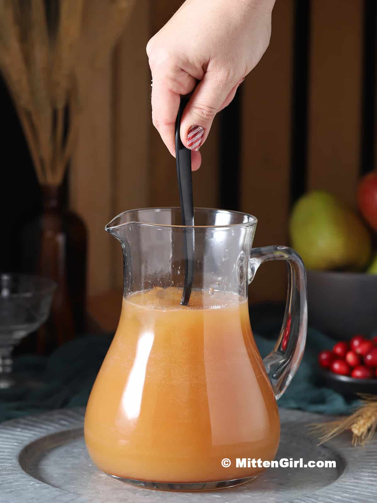 A hand stirring a pitcher of mocktails. 