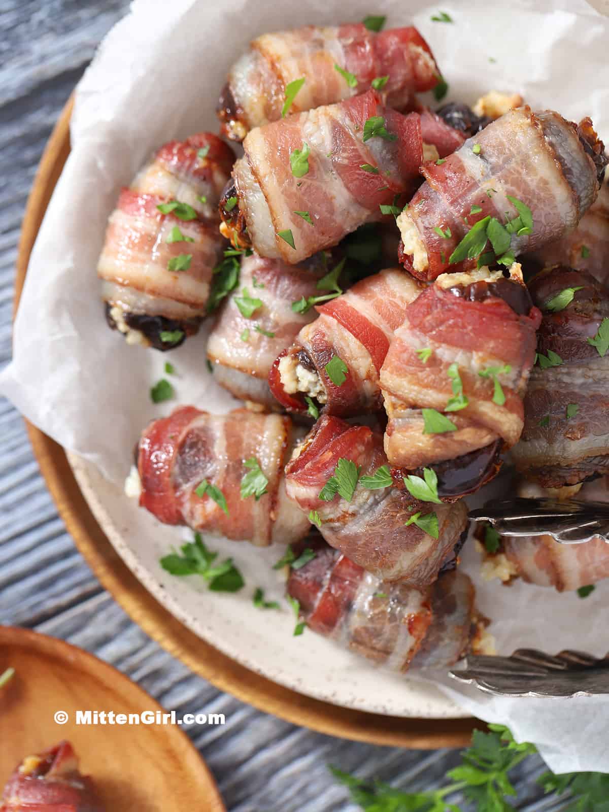 A platter of bacon wrapped dates garnished with parsley.