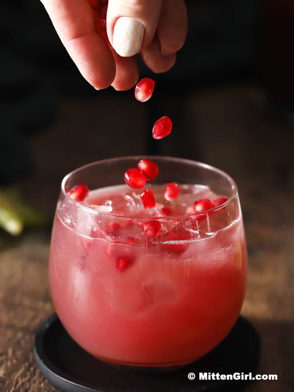 Pomegranate perils being dropped into a glass. 