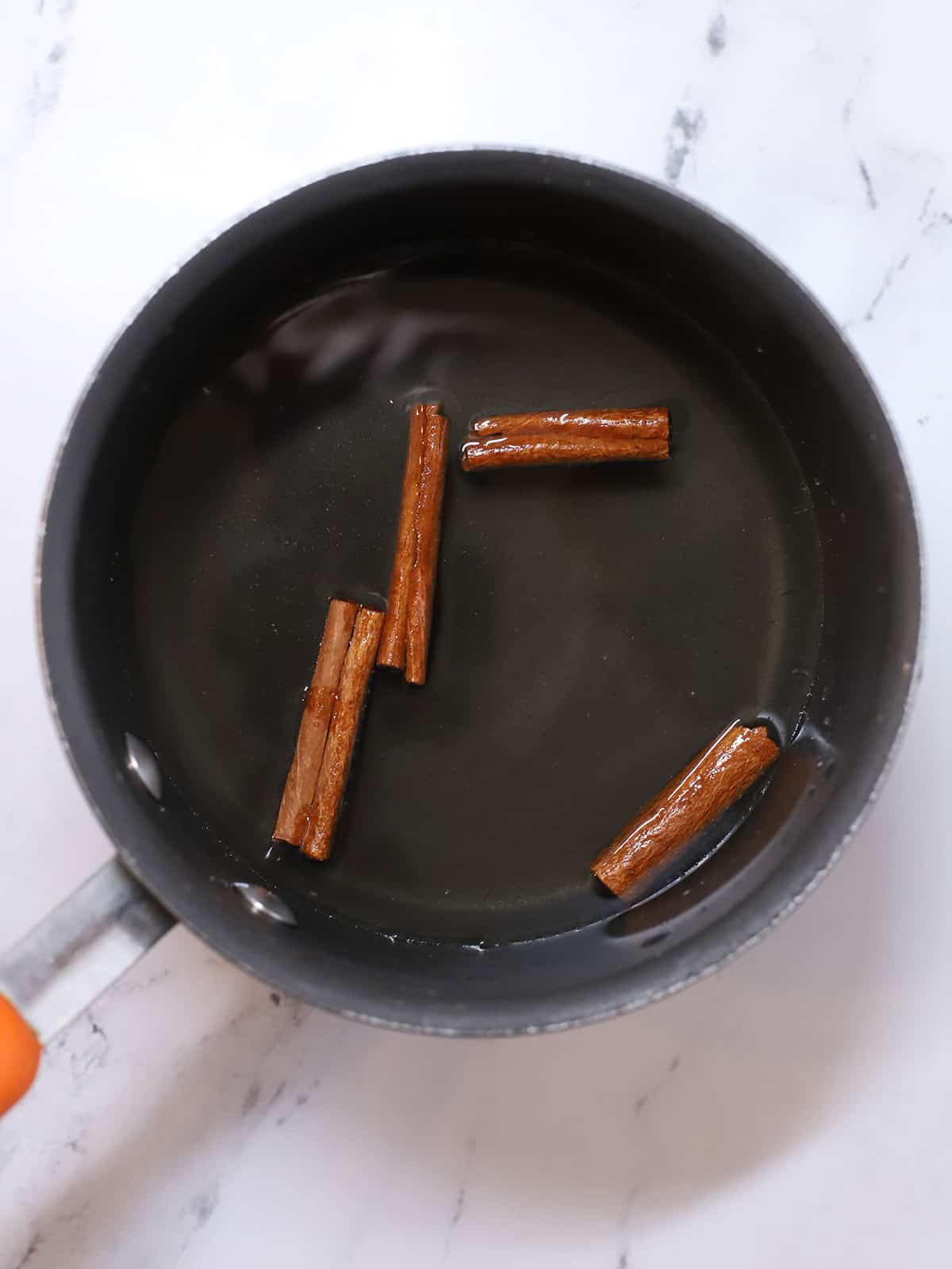 Cinnamon sticks in a pot of hot simple syrup.