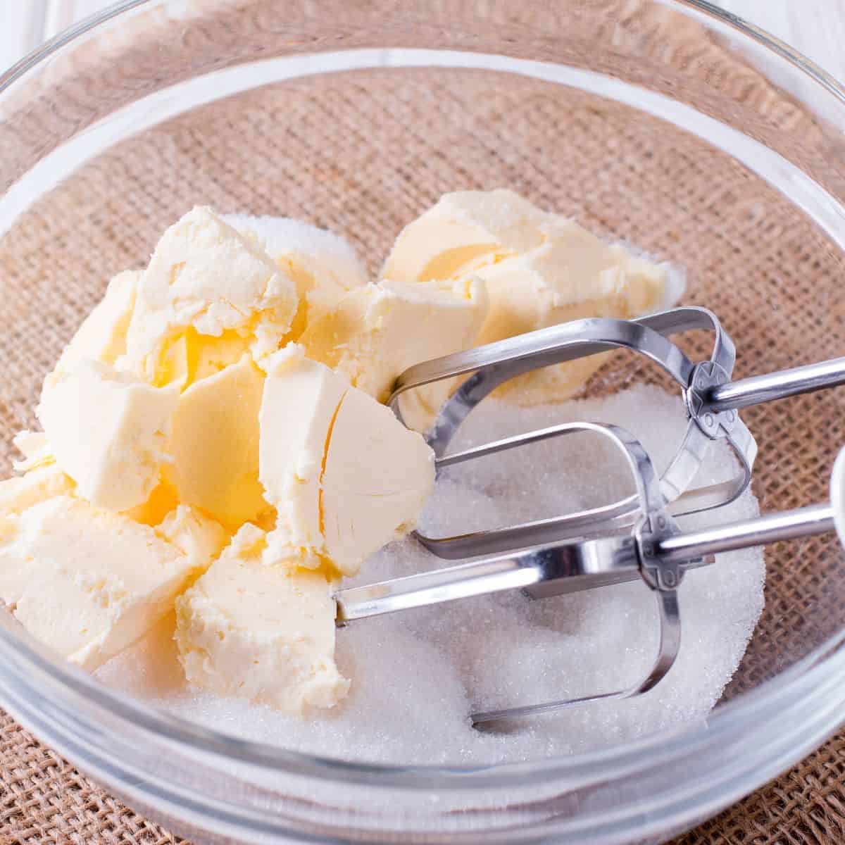 Butter and sugar in a bowl with mixing beaters.
