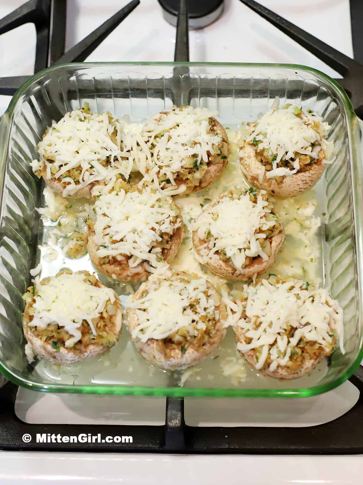 Shredded cheese on top of the stuffed mushrooms.
