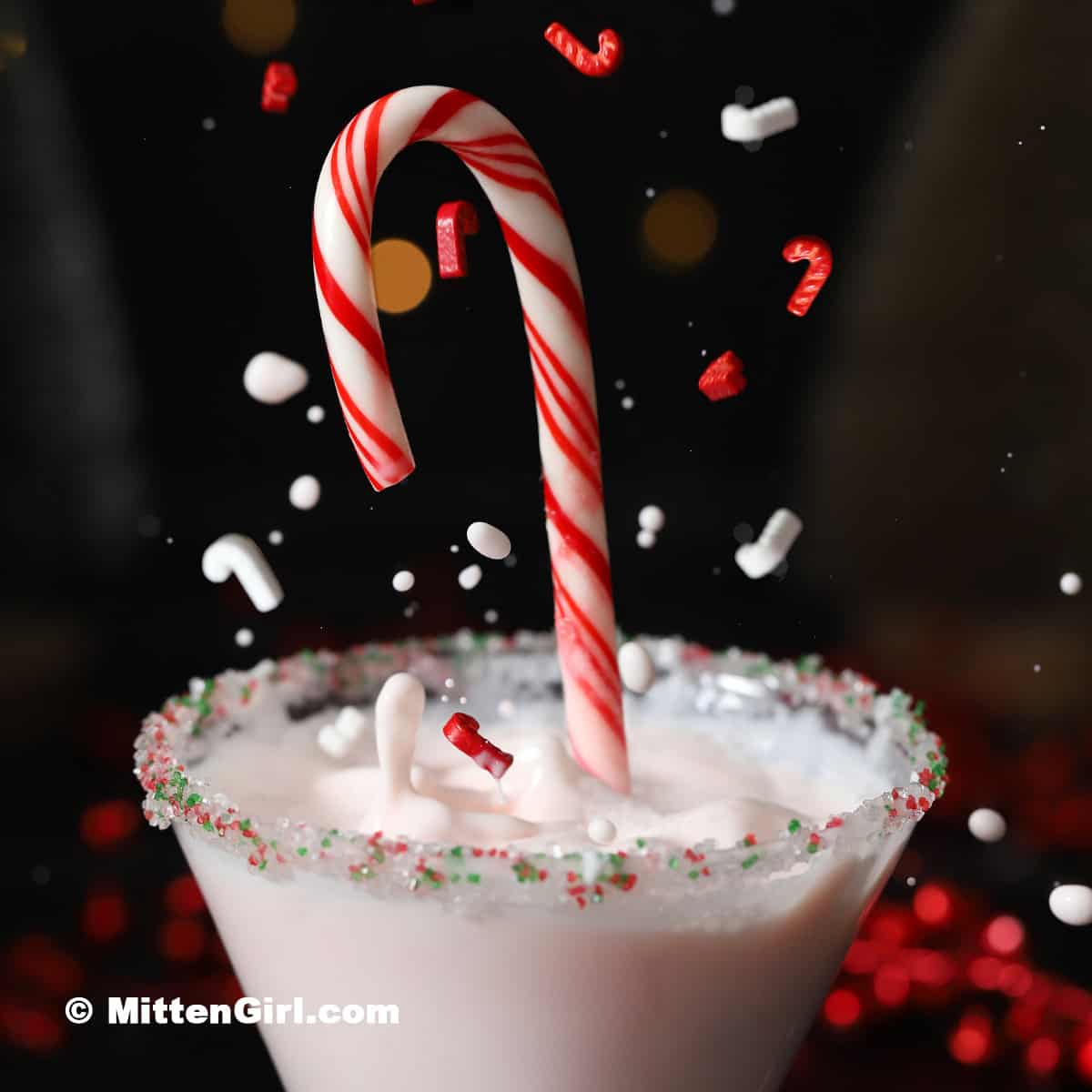 A candy cane splashing into a cocktail.