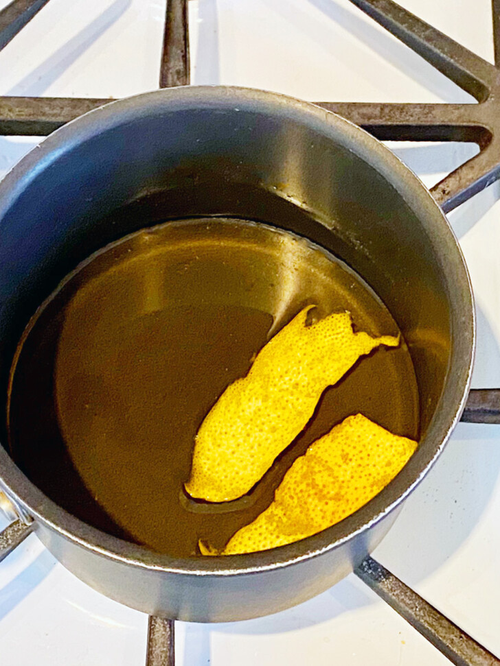 A pair of grapefruit peels floating in a pan on syrup.