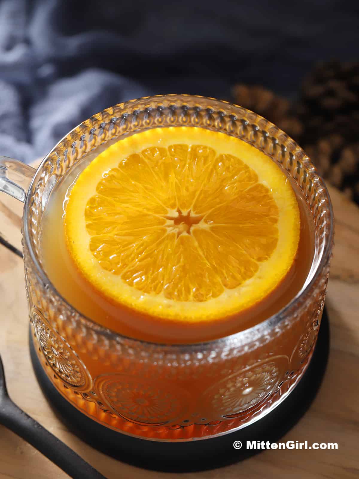 An orange slice floating in a mug of maple hot toddy.