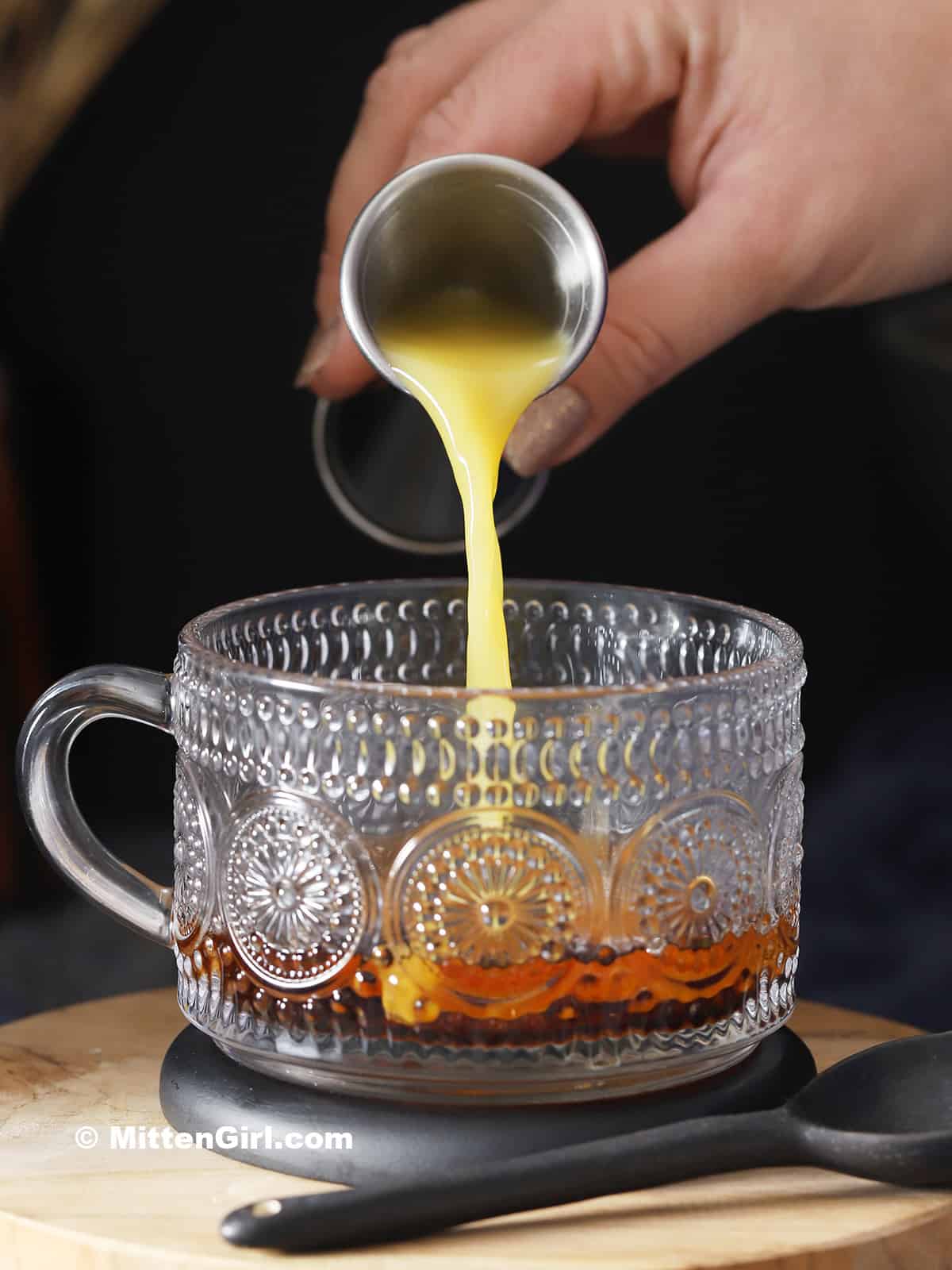Orange juice being poured into a mug.