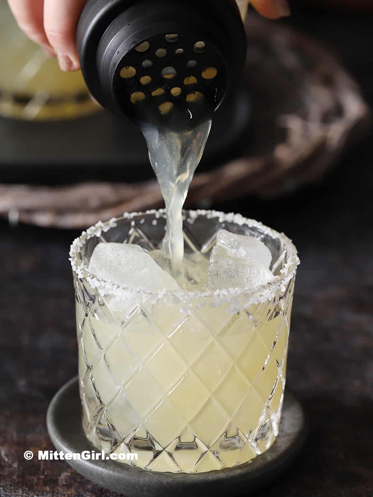 Margarita mocktail being poured into a rocks glass.
