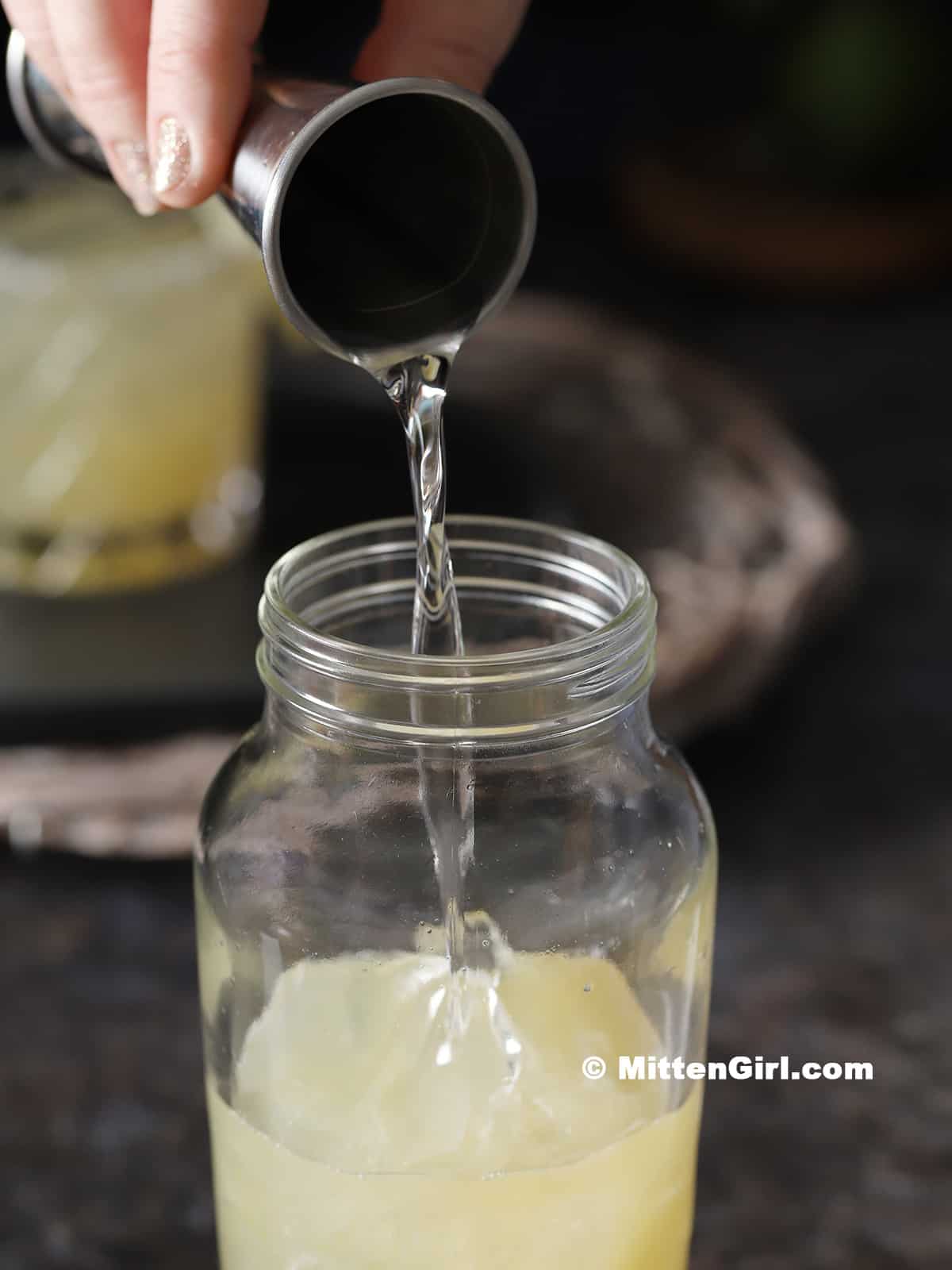 Simple syrup being poured into a cocktail shaker.