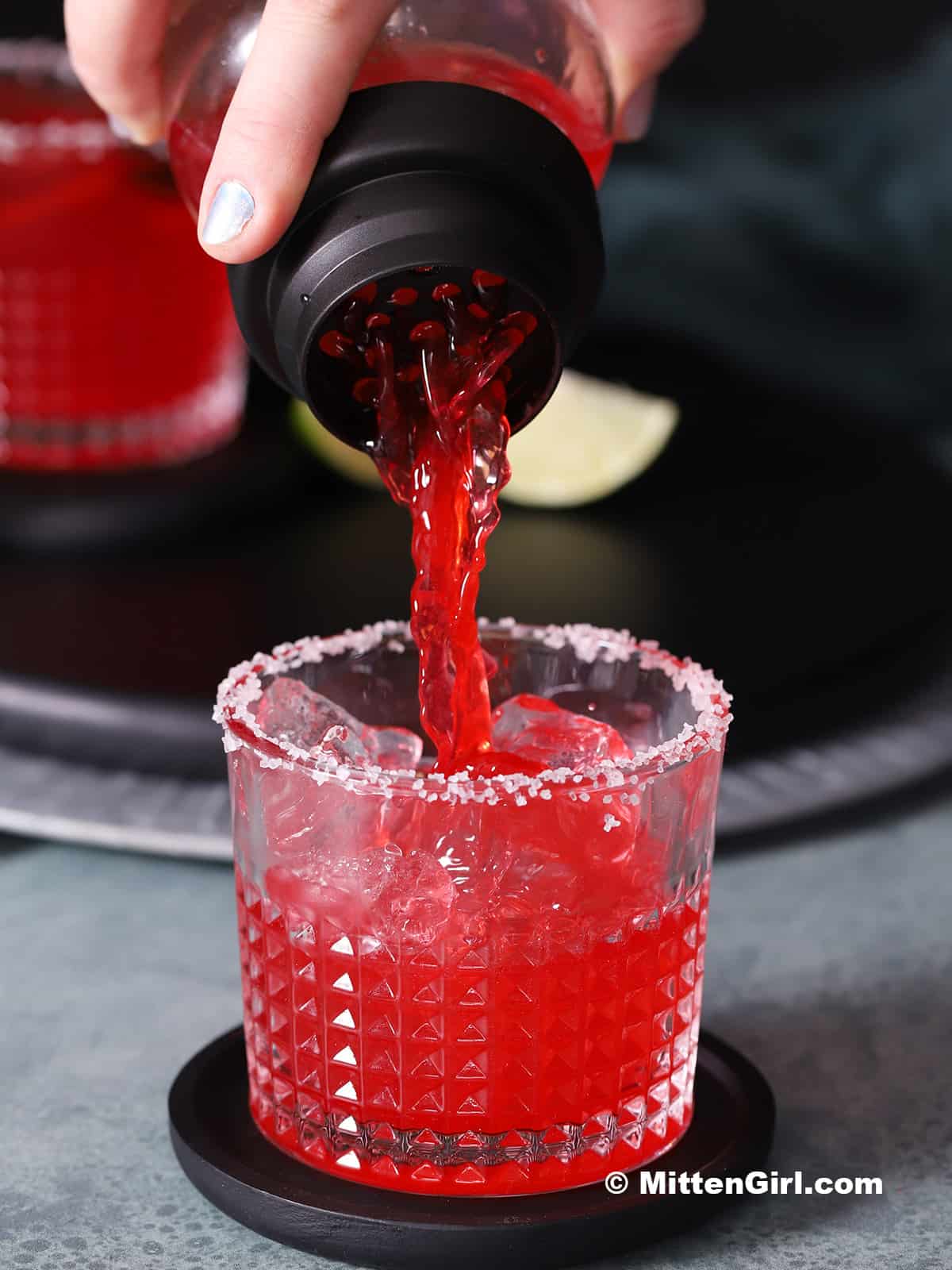 Blackberry margarita being poured into a glass.