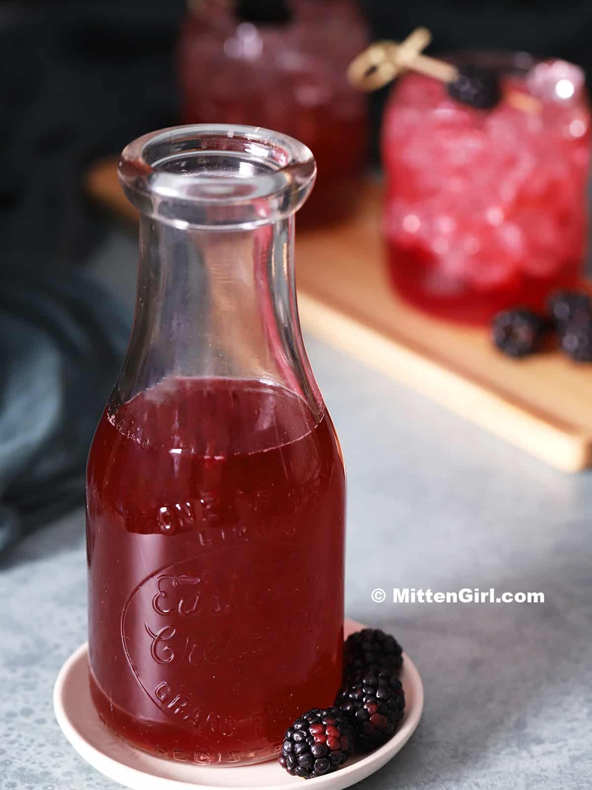 A glass jar of blackberry syrup. 