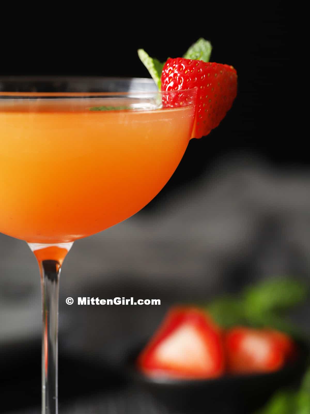 A fresh strawberry on the side of a mocktail.