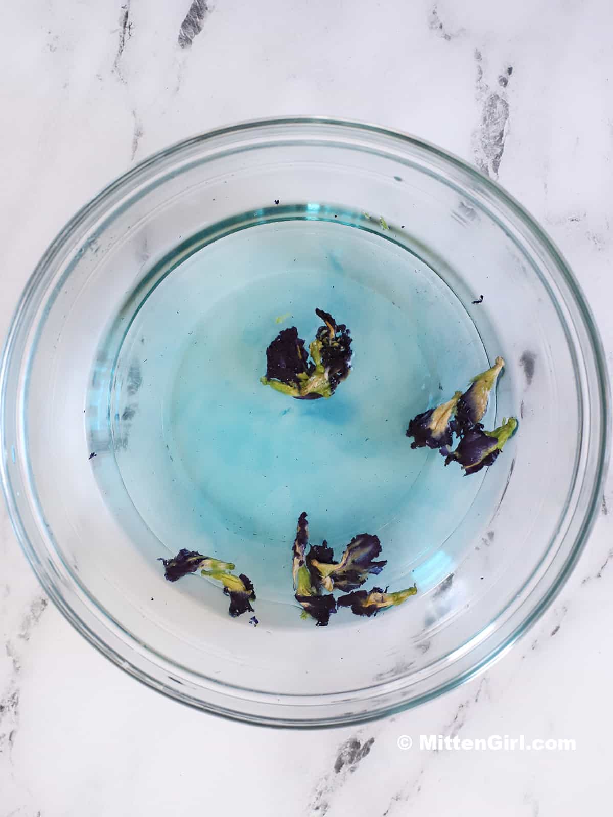 Dried butterfly pea flowers in hot syrup. 