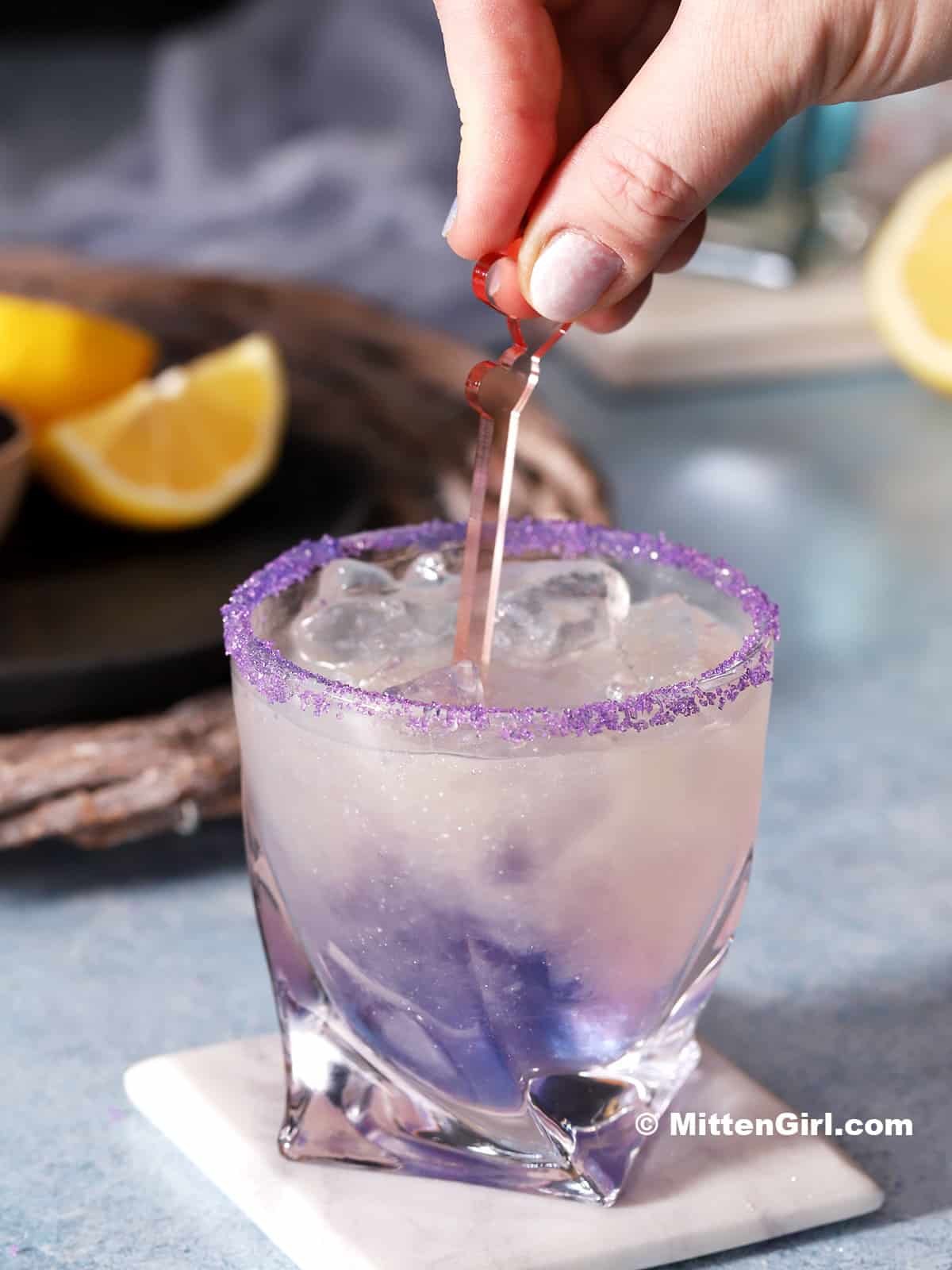 A hand stirring a glass of unicorn lemonade.