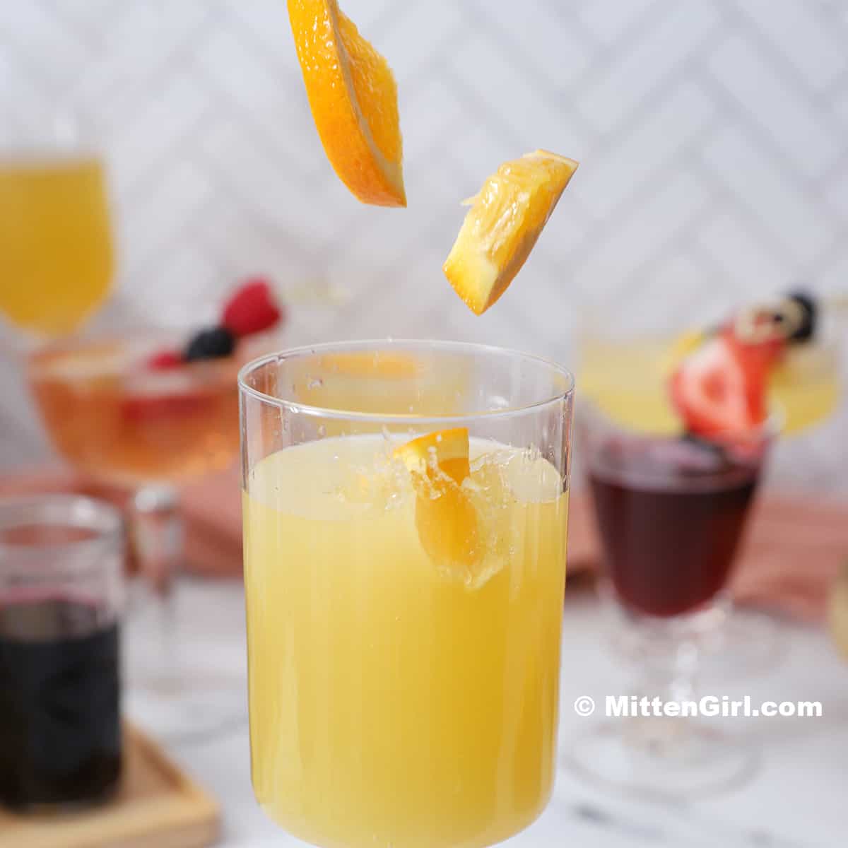 Orange slices falling into a glass of mimosa.