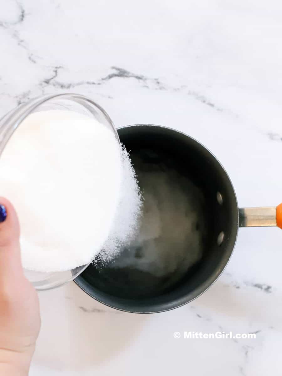 Sugar being poured into a small pot.