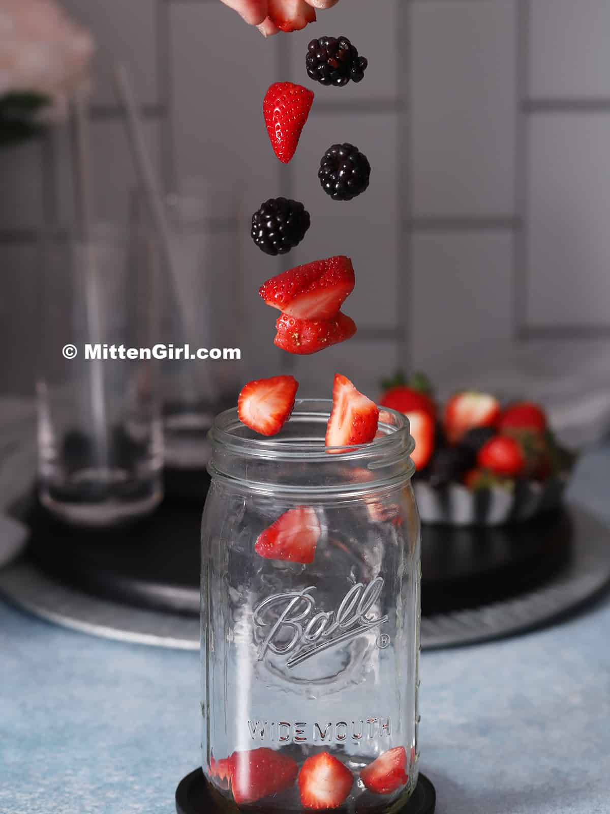 Berries falling into a quart jar.