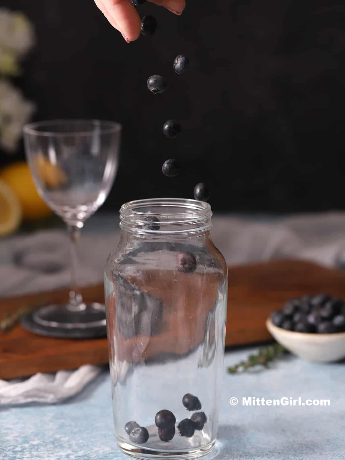 Blueberries dropping into a cocktail shaker.