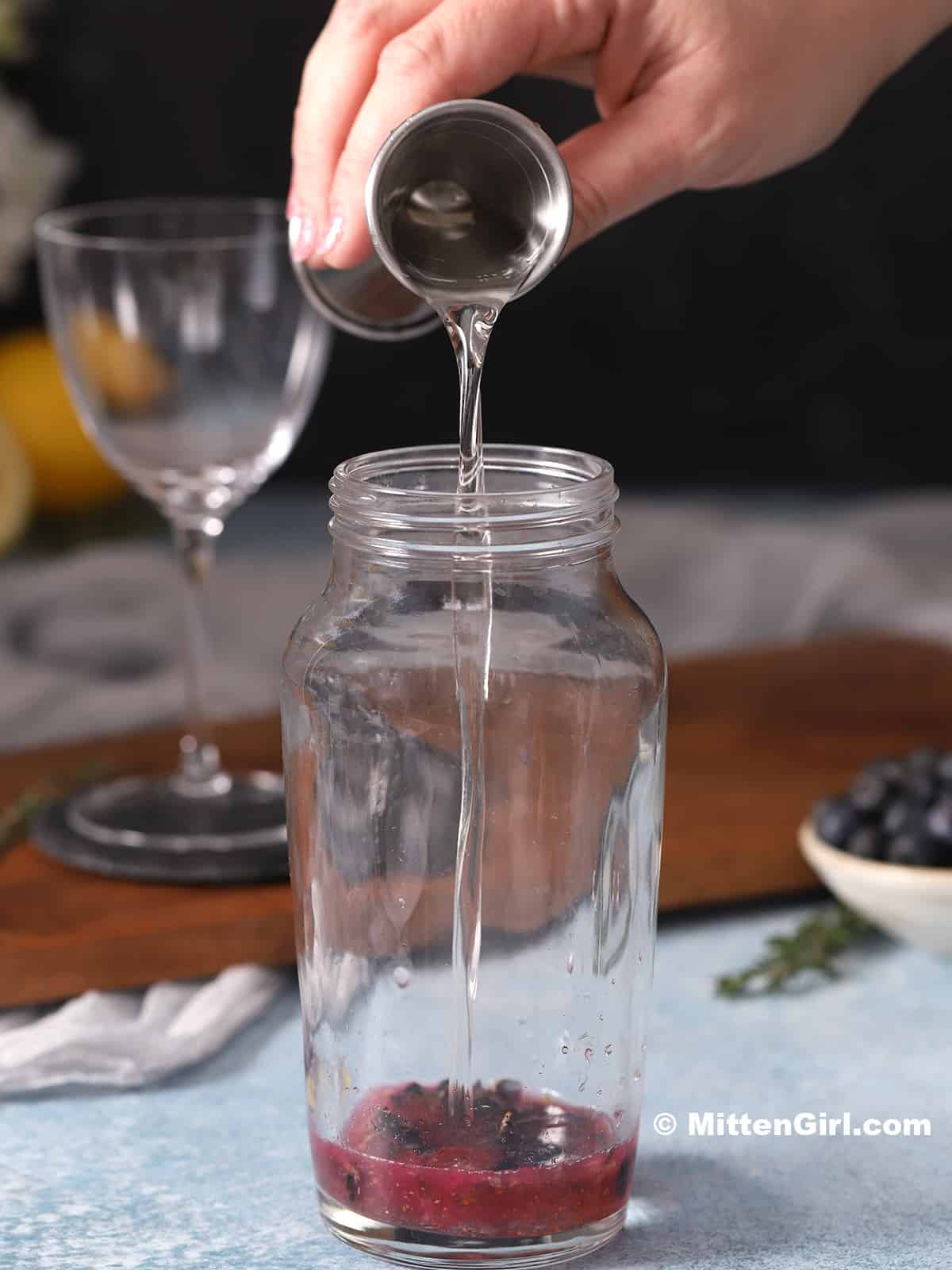Lavender syrup being poured into a cocktail shaker.