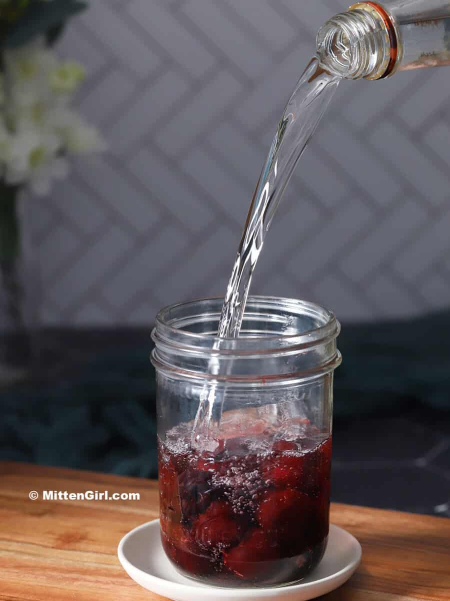 Vodka being poured into a mason jar.