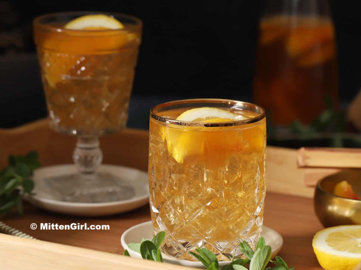 Glasses of ginger peach iced tea on coasters sitting on a wooden tray.