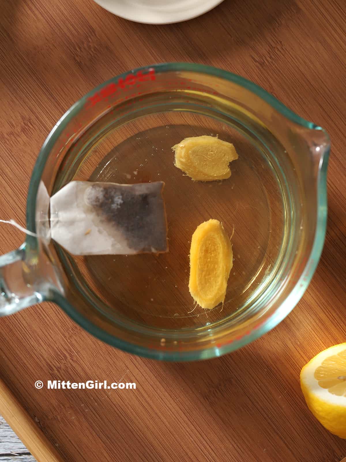 Ginger root and a tea bag floating in hot water.