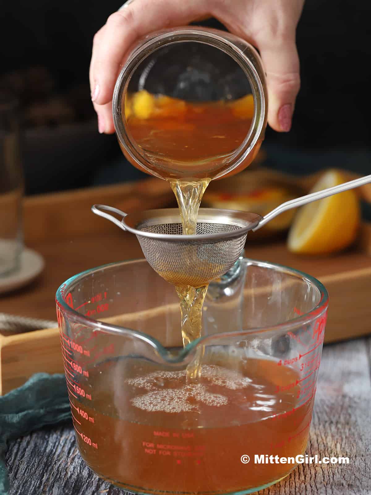 Ginger Peach Iced Tea being poured through a fine mesh strainer.