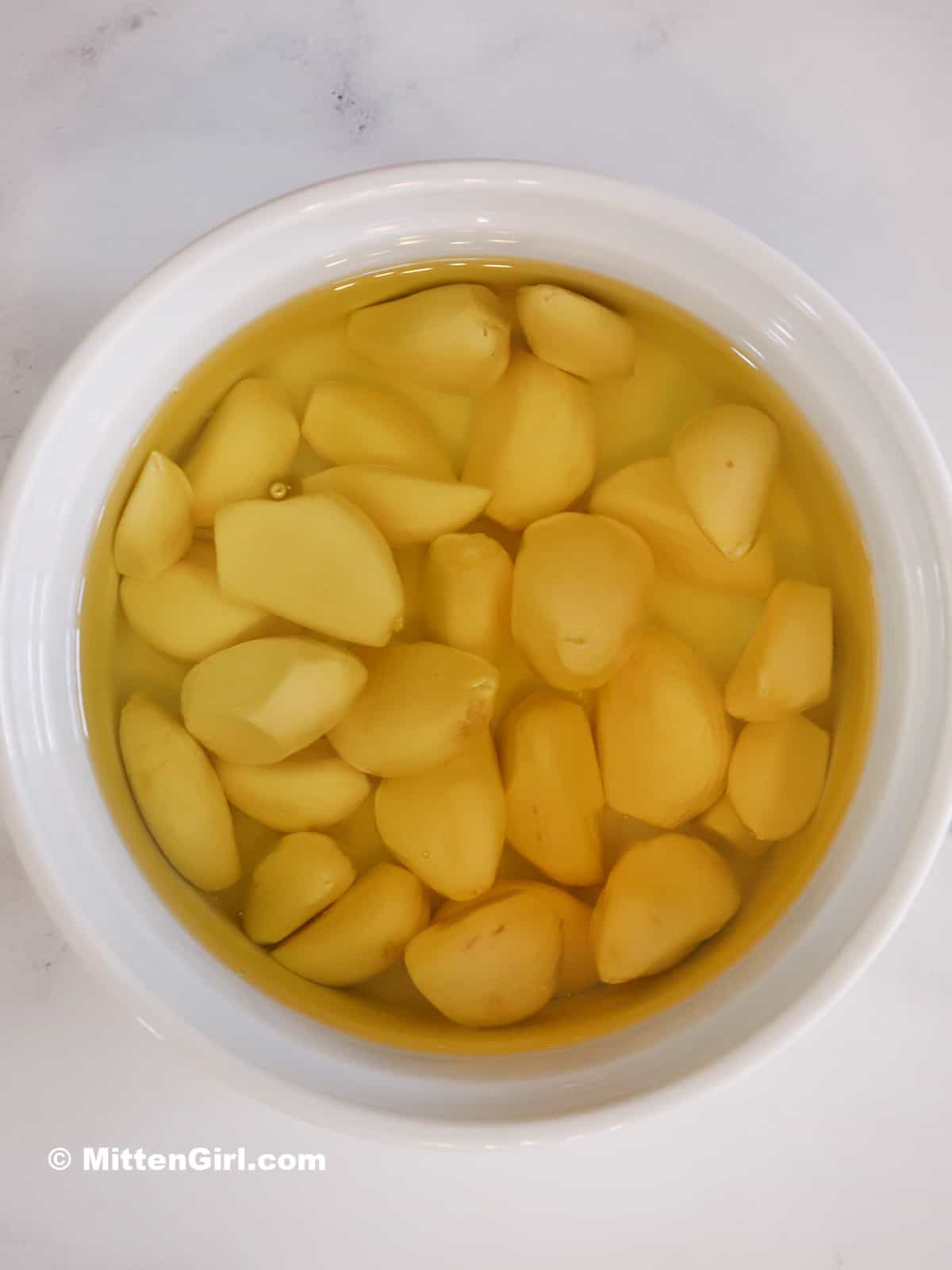 Peeled garlic and olive oil in a baking dish.