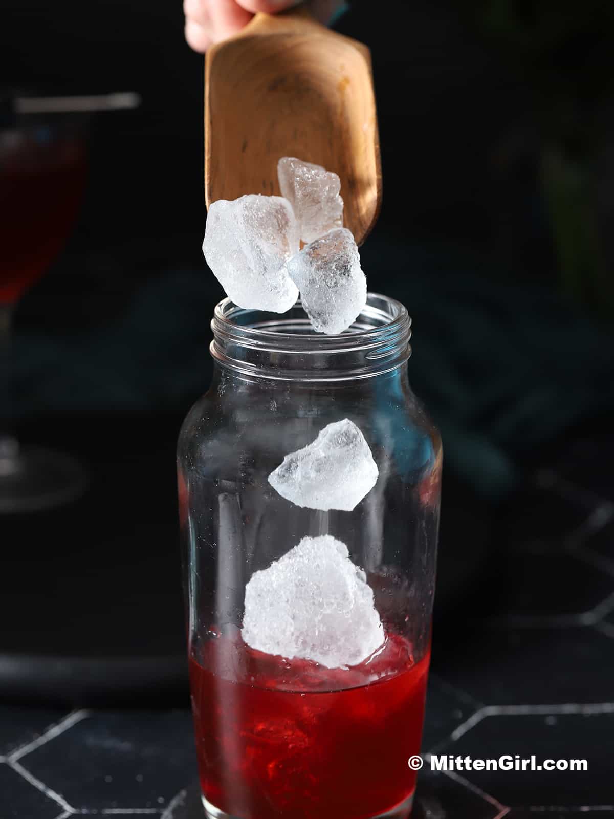 Ice cubes being poured into a cocktail shaker.