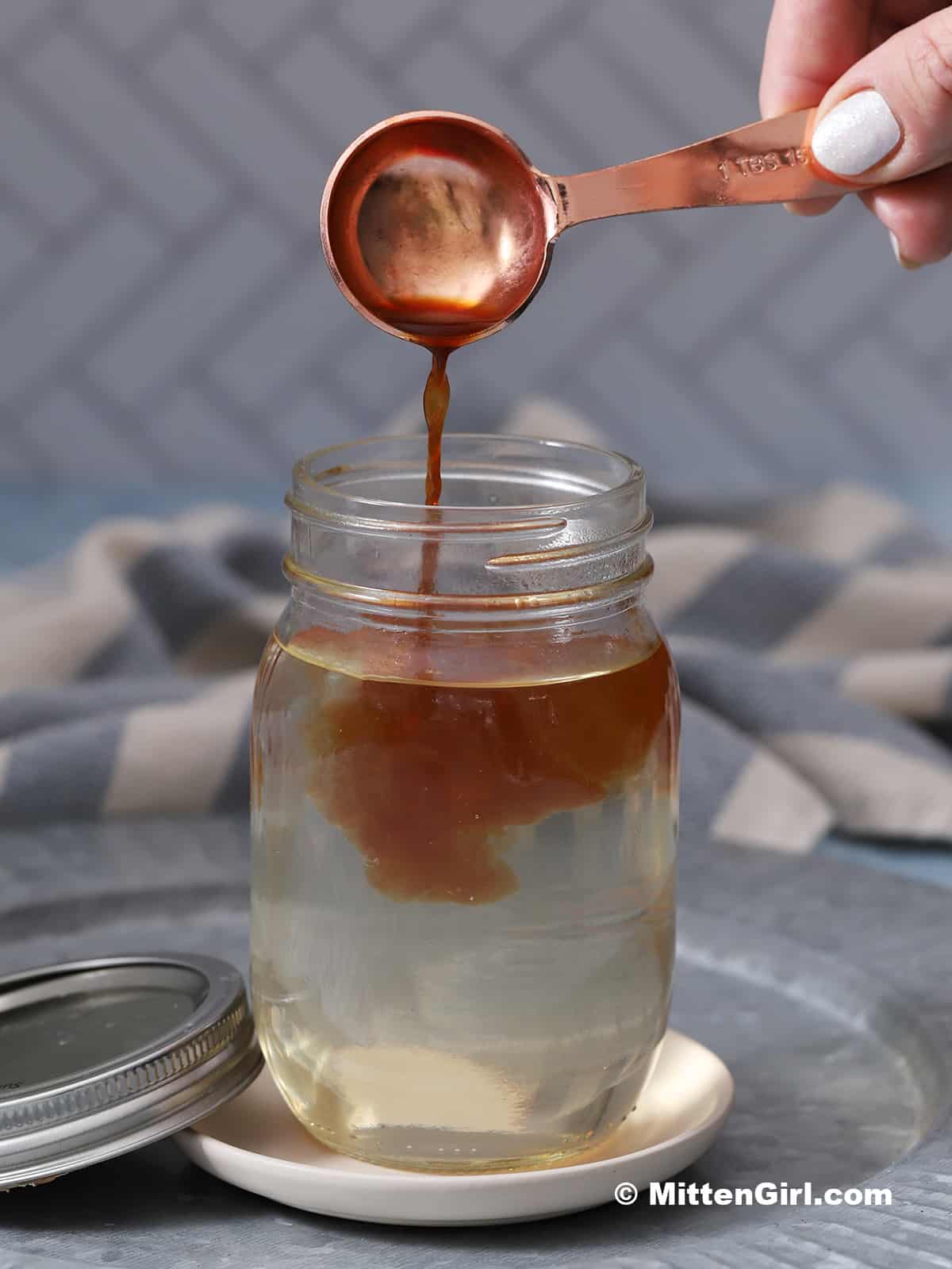 Vanilla extract being poured into a jar of syrup.