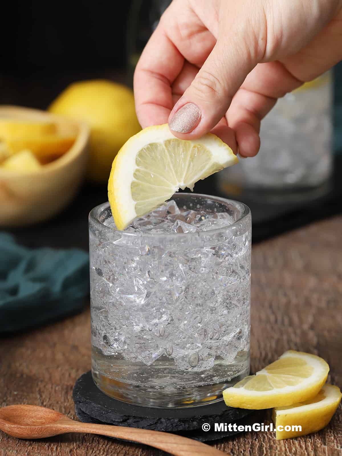 A hand placing a slice of lemon on a drink. 