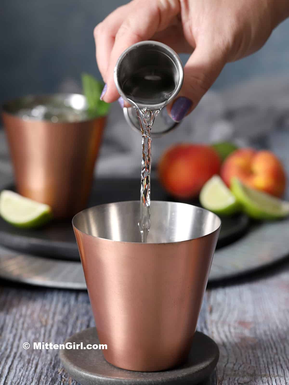 Vodka being poured into a copper cup. 