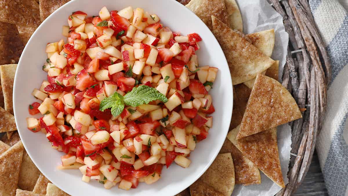 A bowl of fresh apple salsa surrounded by cinnamon tortilla chips.