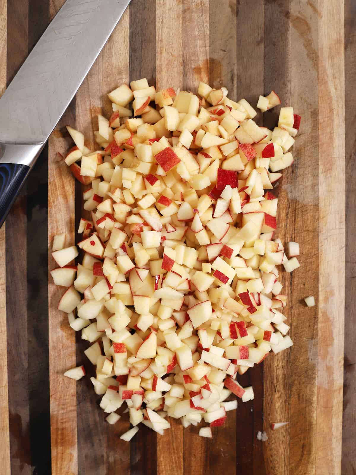 A wooden cutting board full of diced apples.