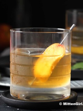 A glass of peach old fashioned cocktail.